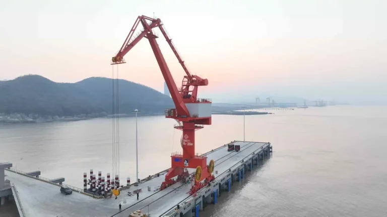 Portal harbor crane working above a waterfront cargo berth