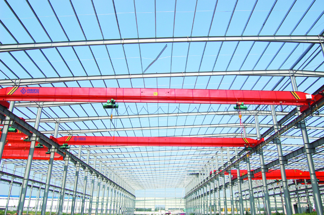 Single-girder overhead cranes operating across an industrial workshop