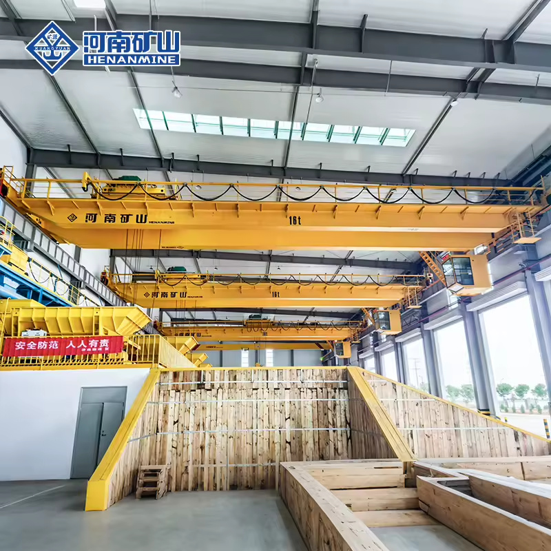 Yellow double-girder overhead cranes with winch trolleys and operator cabins in a workshop