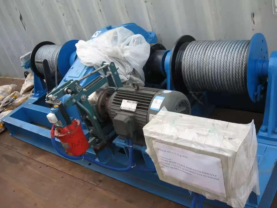 Close view of a JM single-drum winch motor, brake linkage and rope drum