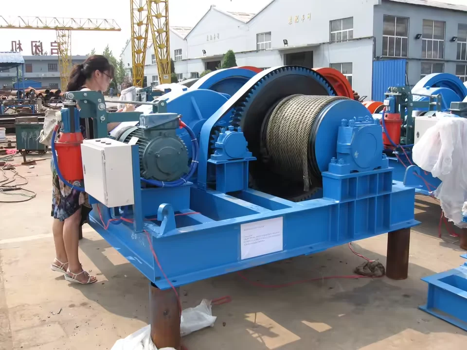 JM electric wire rope winch photographed at the factory with a person for scale