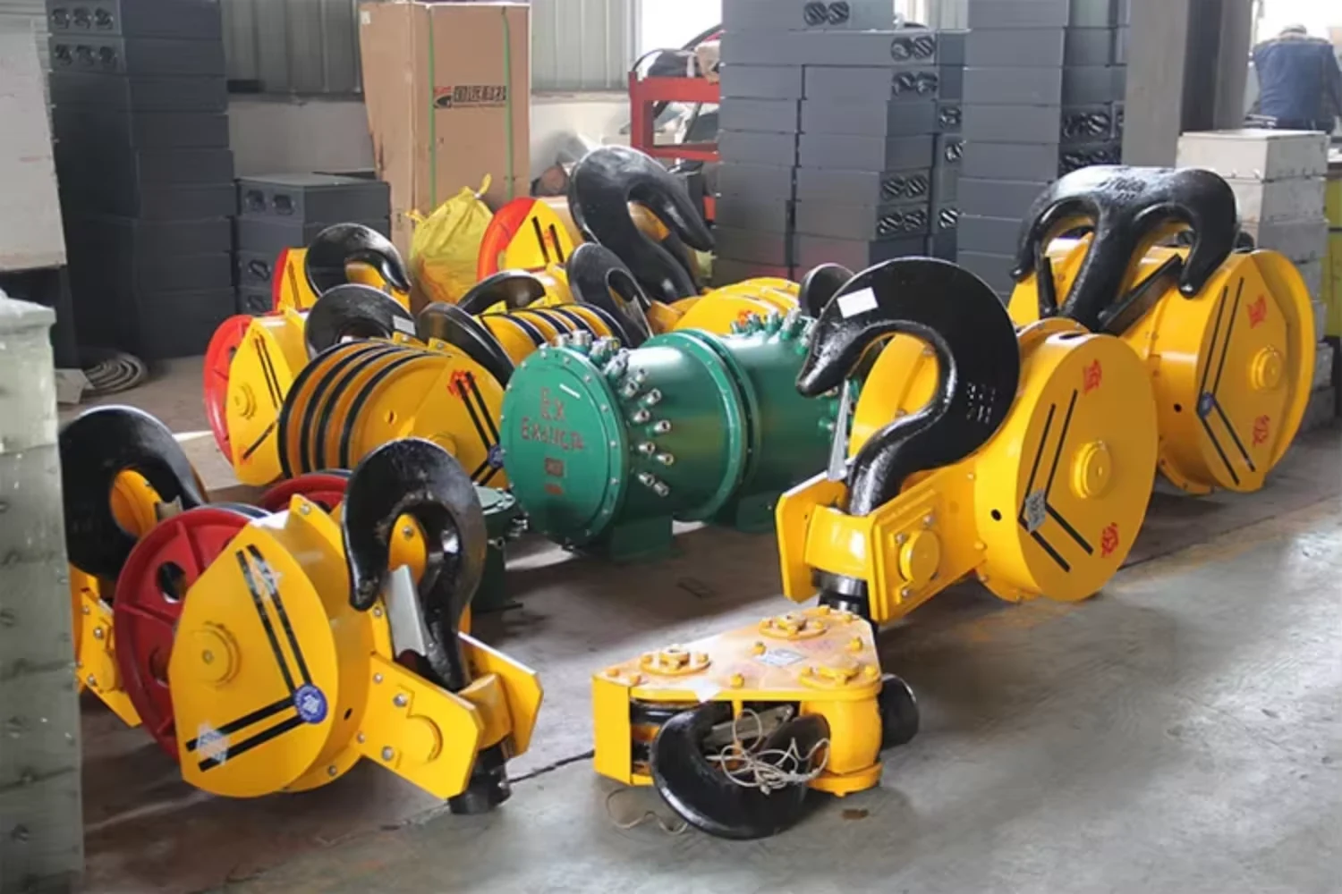 Yellow crane hook blocks with forged hooks and sheaves on a workshop floor