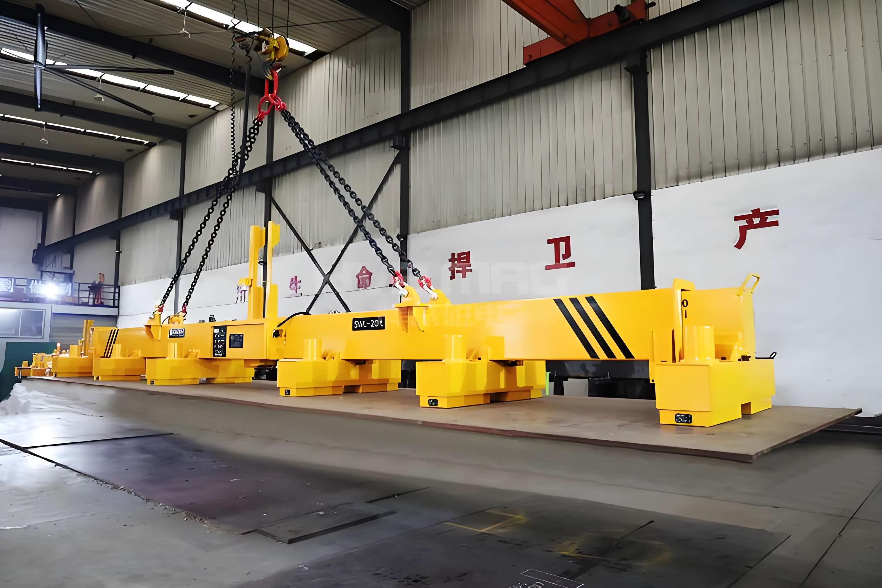 Full-length yellow lifting beam with multiple suspended magnetic units in a factory