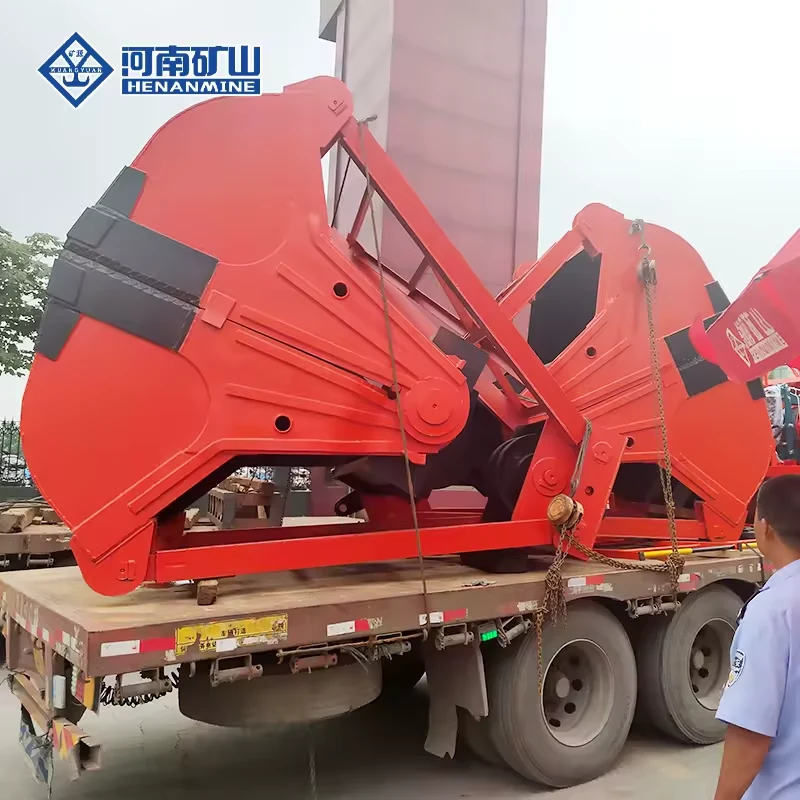 Large red clamshell grab assemblies secured for transport on a flatbed truck