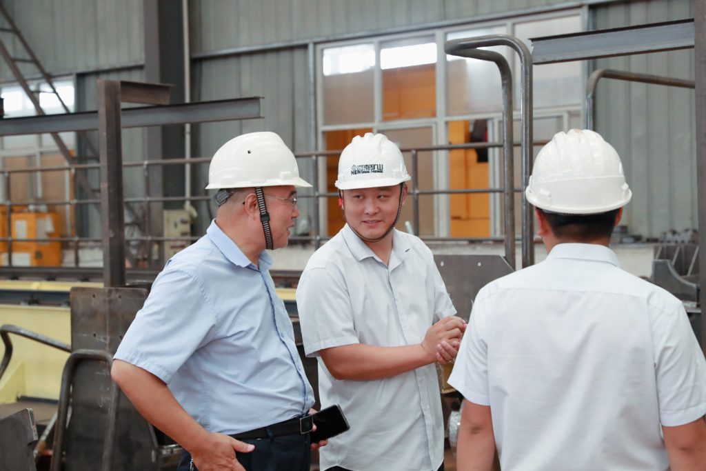 Factory inspection team discussing crane acceptance measurements