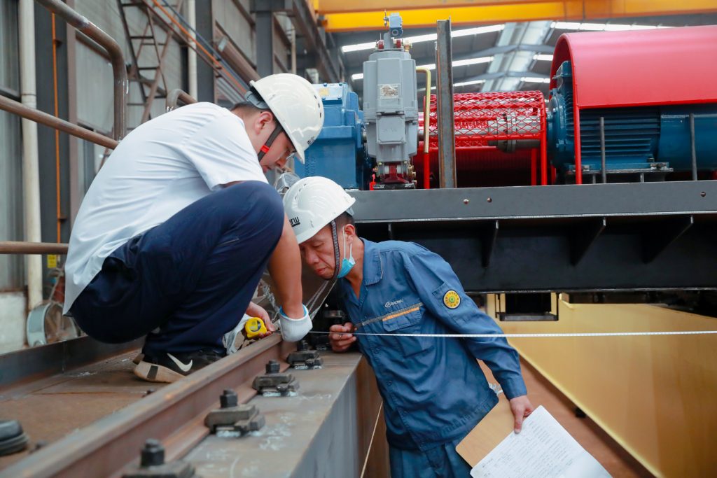 Inspectors measuring crane trolley rail and structural dimensions
