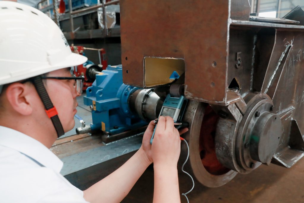 Inspector checking crane drive machinery with a measuring instrument