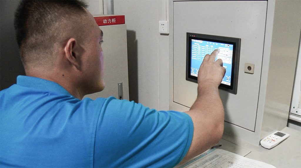 Operator using the touchscreen control panel of an automated storage crane
